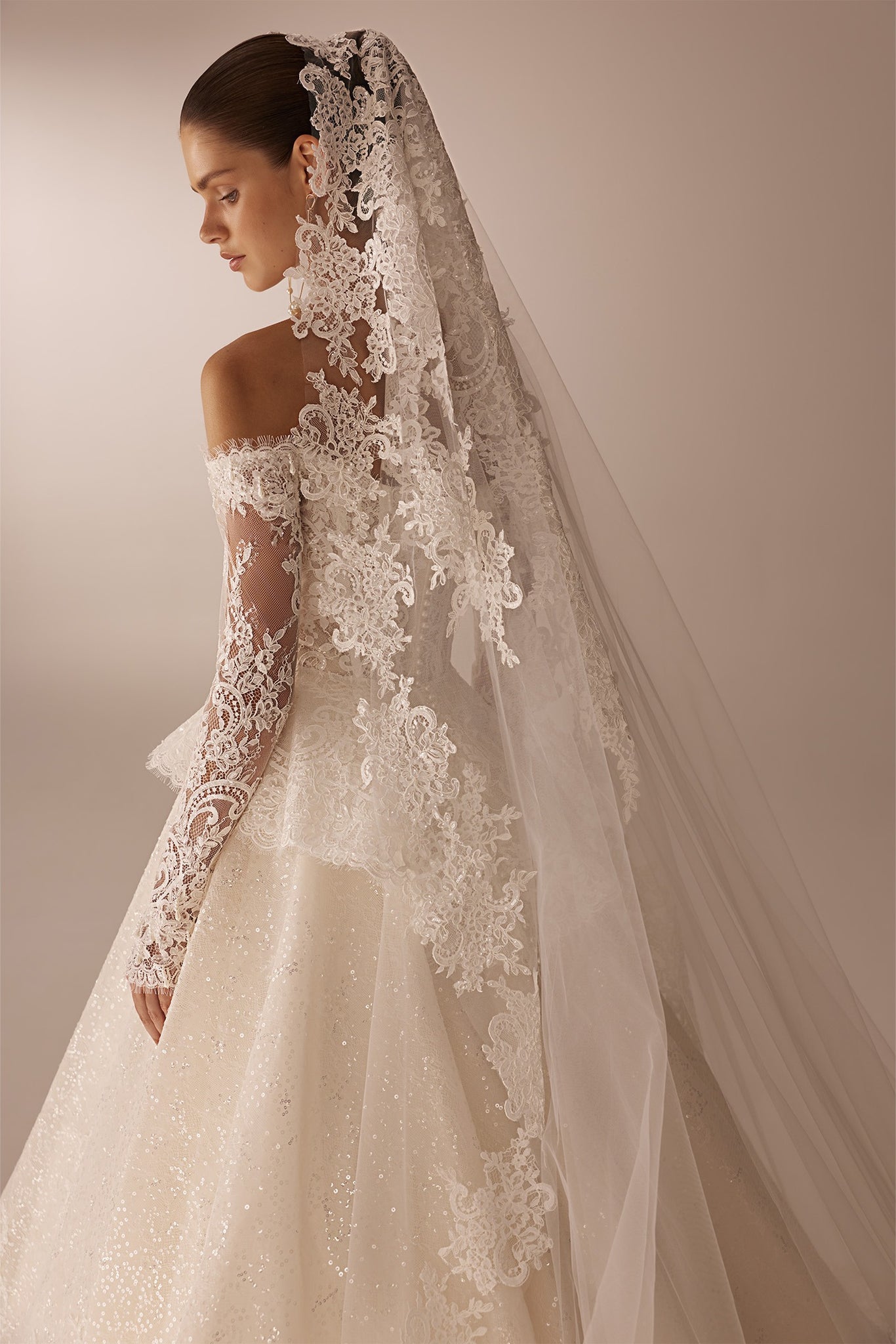 Bride wearing an off the shoulder lace wedding dress with long sleeves and a matching lace veil