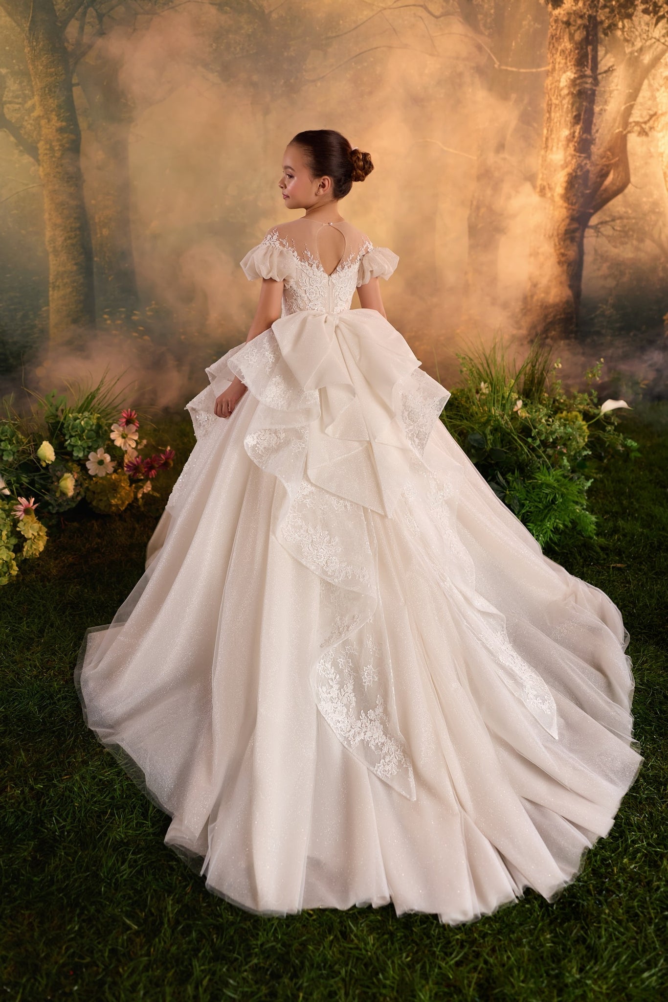 Girl wearing a white lace ball gown with a long train and puff sleeves