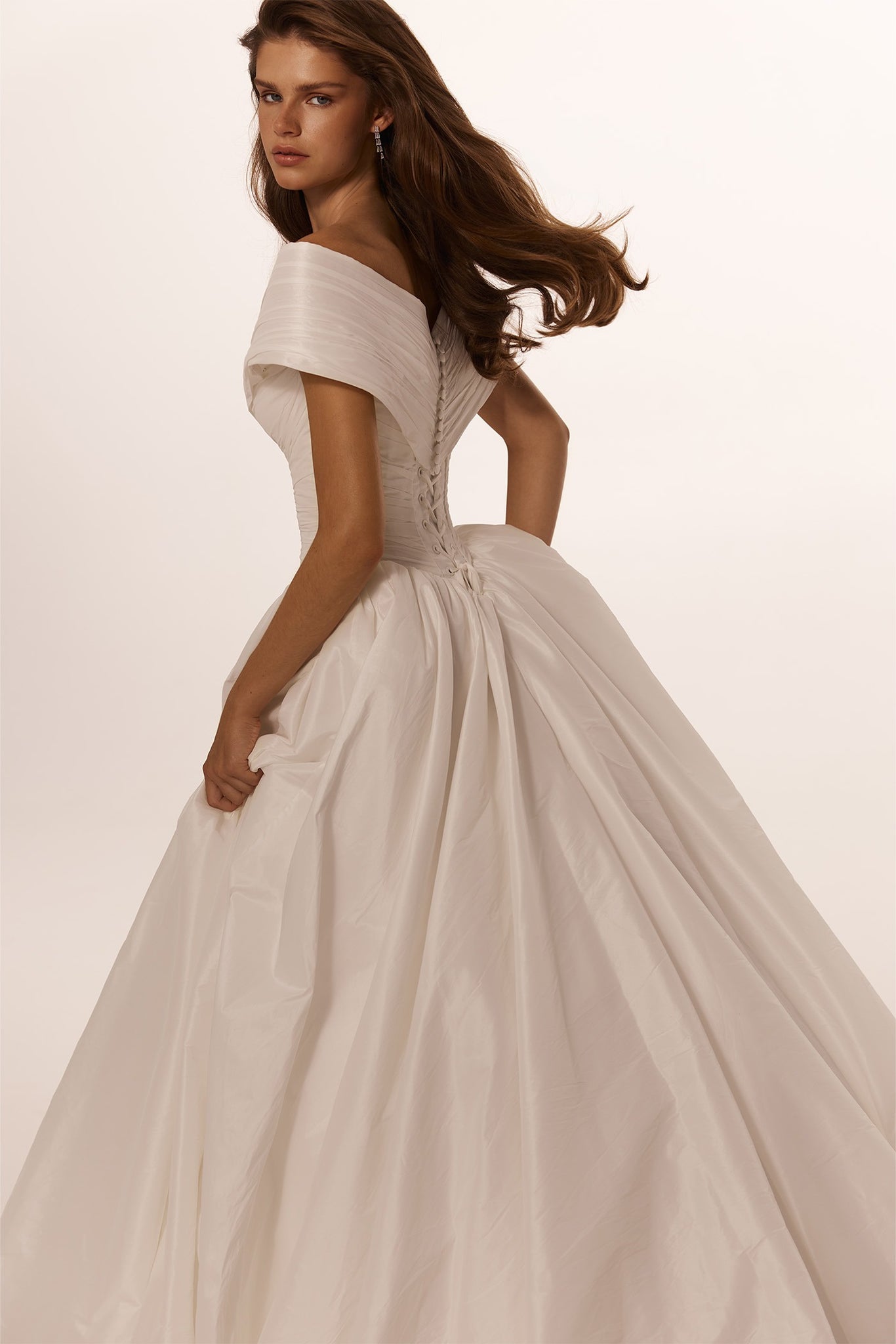 Woman wearing an off the shoulder white ballgown with a corset back