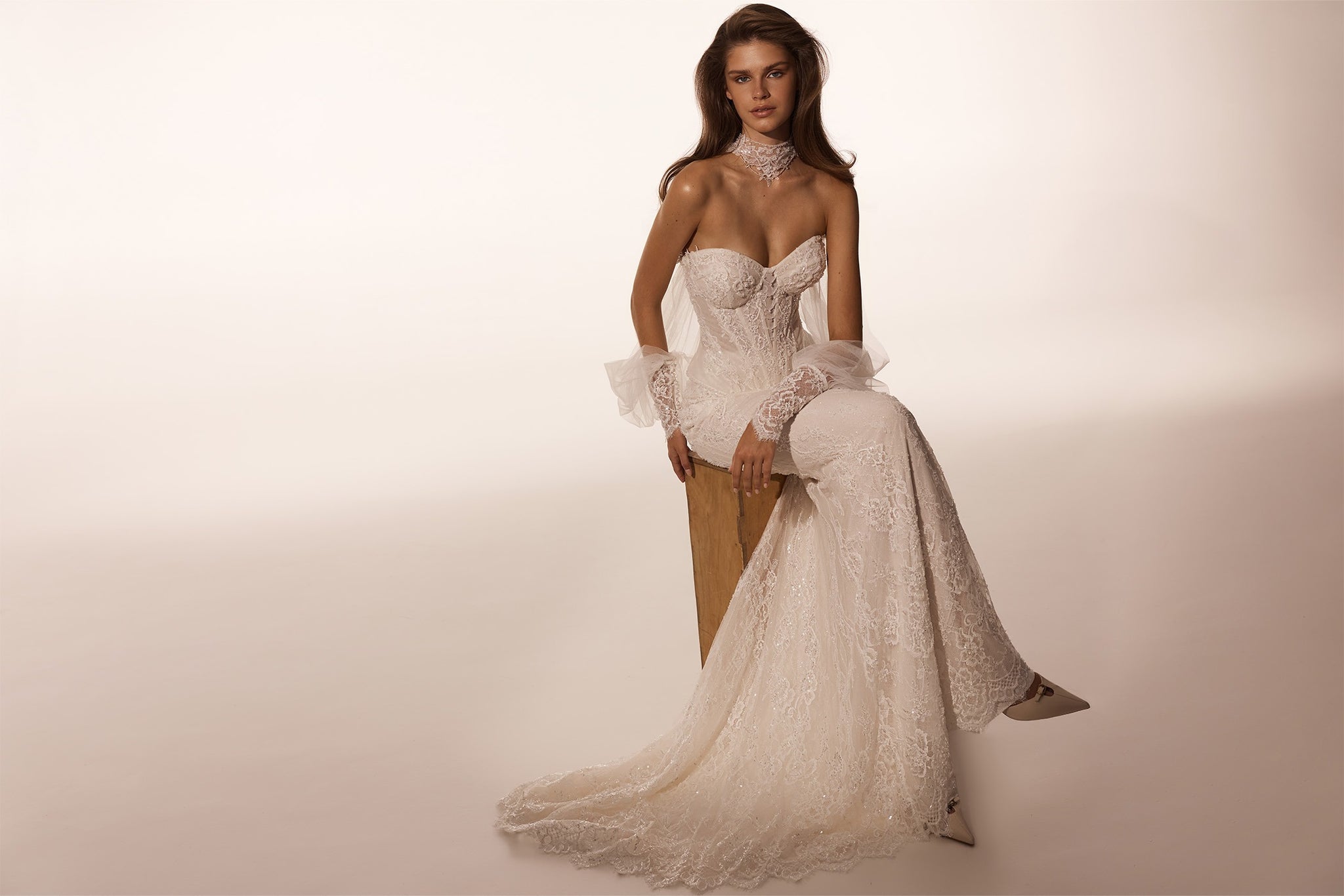 Model wearing a strapless lace wedding dress with a high neck choker and sheer detachable sleeves
