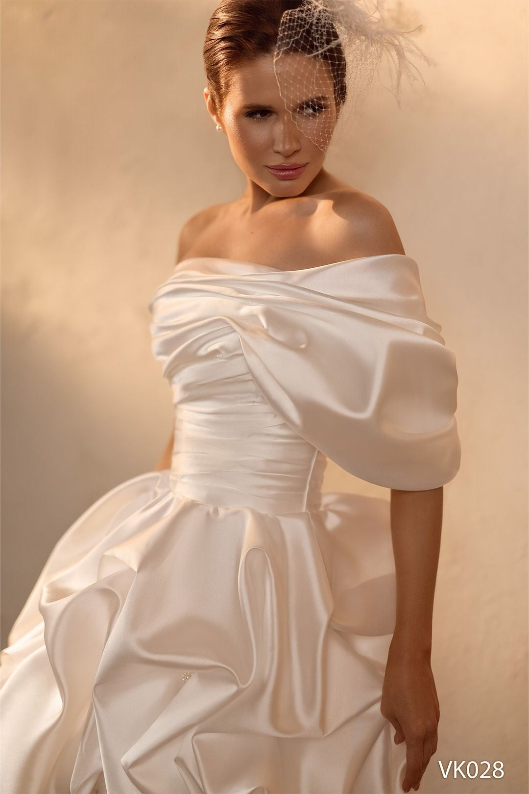 Modern bridal mini dress with asymmetrical off-shoulder neckline, sculptural draped bodice, voluminous bubble skirt, and lace-up back