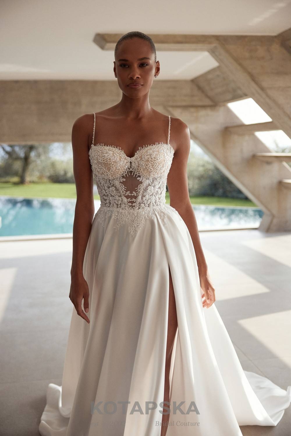 Satin A-line wedding dress with a lace corset bodice, sheer waist inserts, delicate straps, high slit, and a flowing train