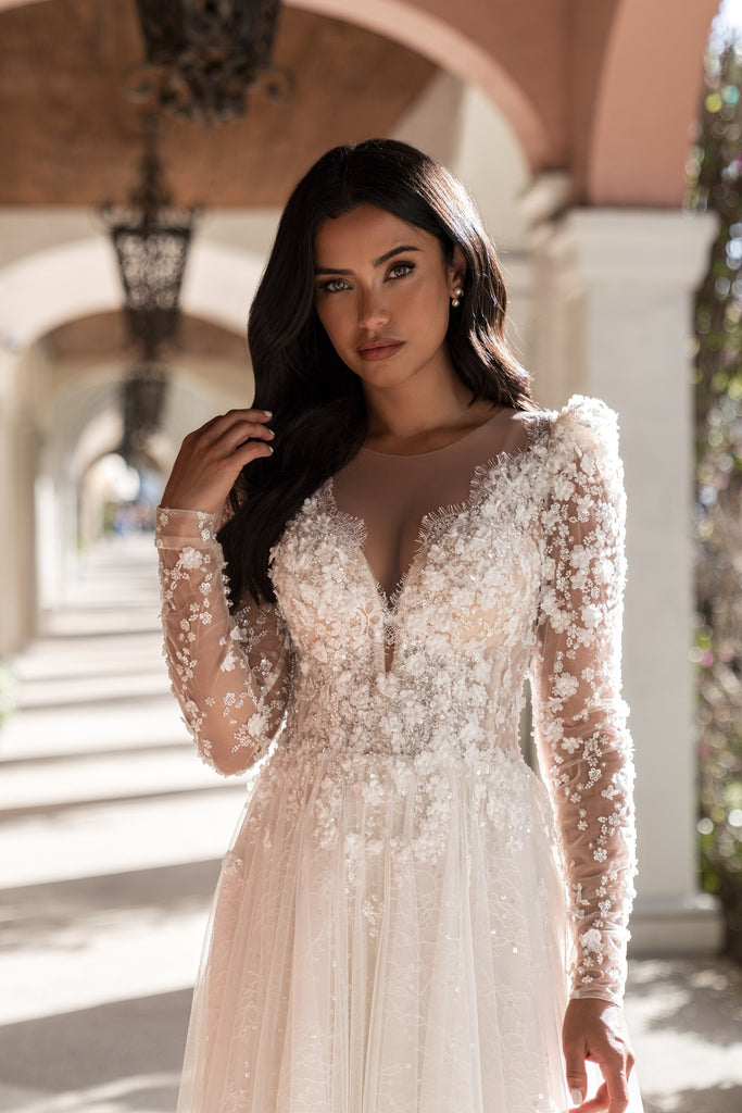 EMABRIDE 275 wedding dress with deep illusion neckline, long sleeves, floral appliqué bodice, and soft A-line skirt