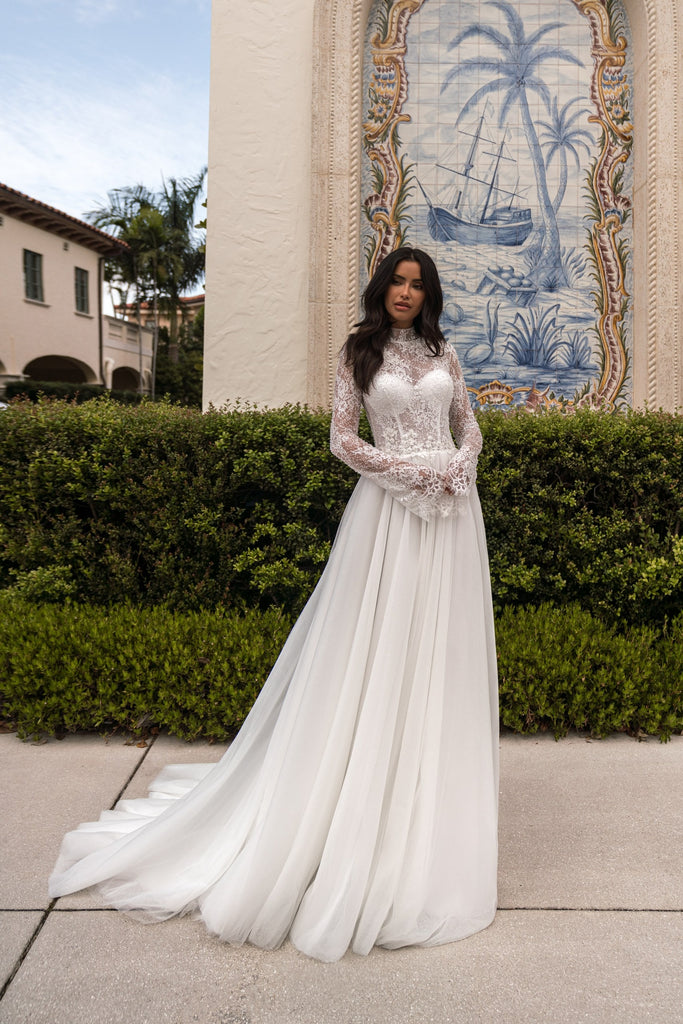 EMABRIDE 281 wedding dress with high lace neckline, long sleeves, bell cuffs, lace bodice, and flowing A-line skirt