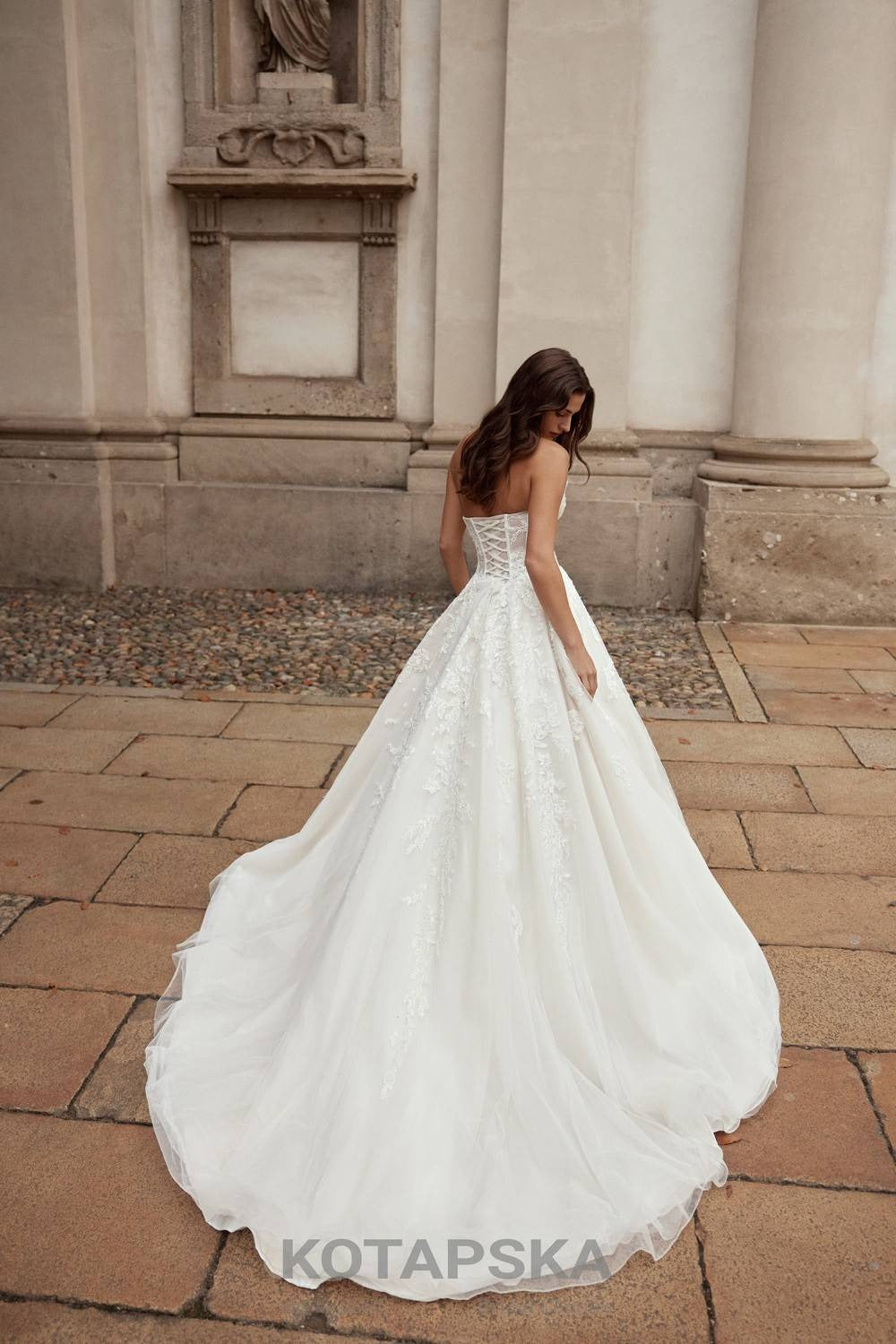 Back view of a lace wedding dress with corset lacing, voluminous tulle skirt, and long flowing train