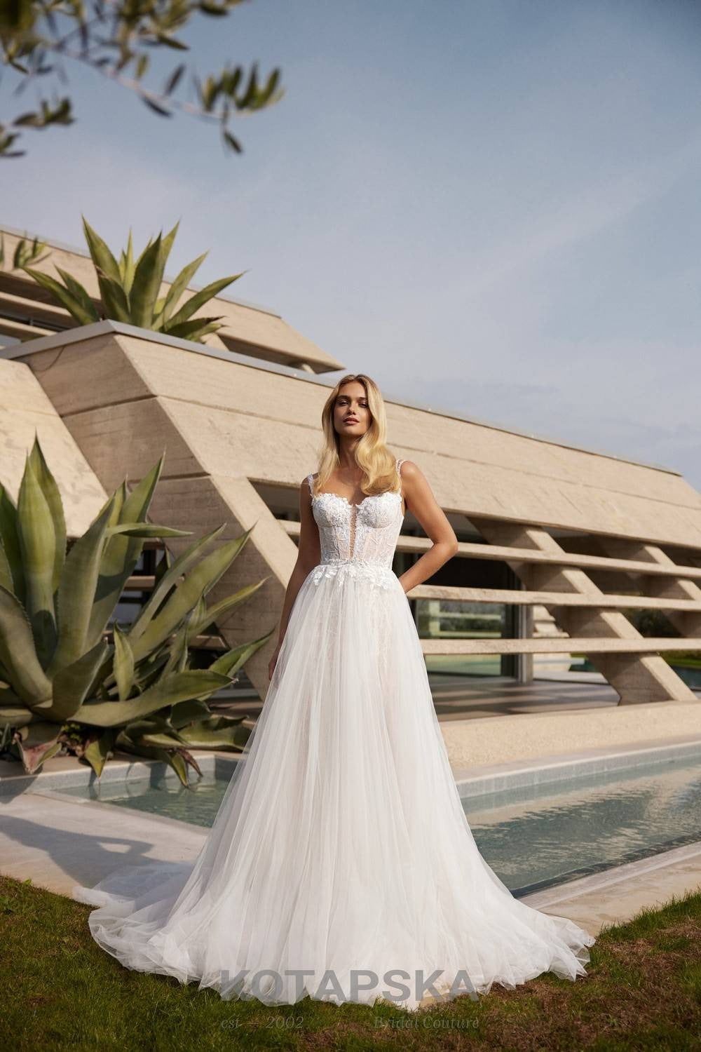 Lace corset wedding dress with delicate straps, illusion bodice, fitted silhouette, thigh-high slit, and a soft flowing train