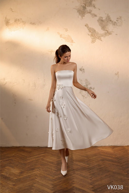 Modern strapless bridal dress with floral appliqués, flowing midi and mini skirt options, and detachable cape