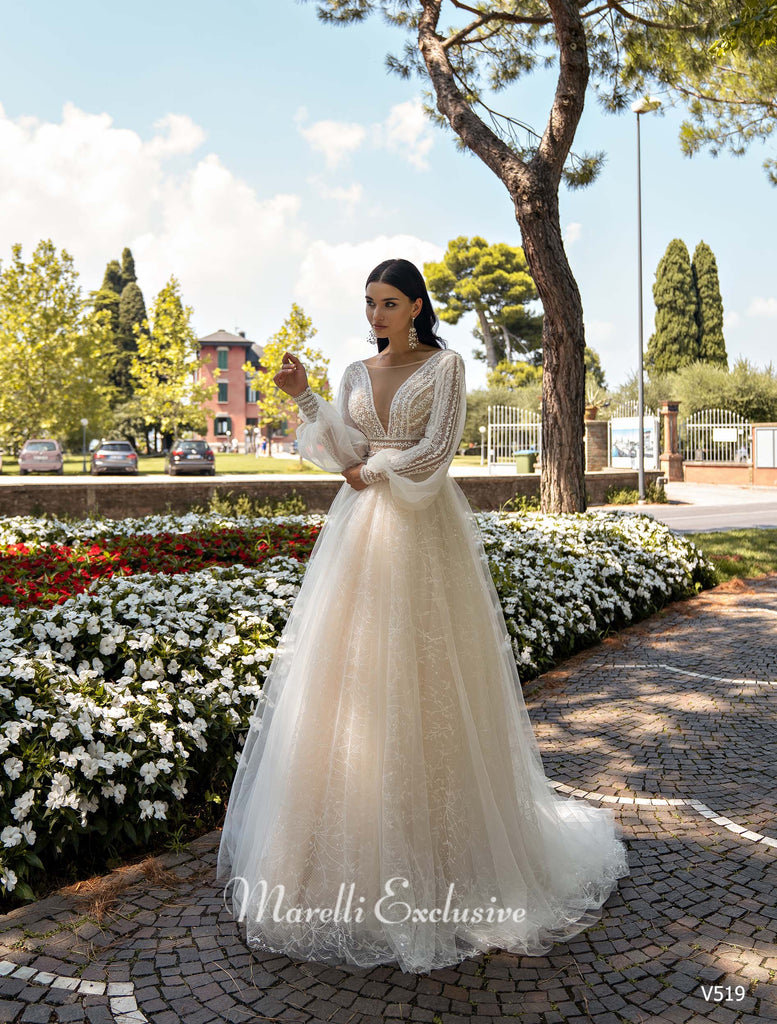 Woman wearing a long sleeve lace wedding dress with a deep V neckline standing in a garden